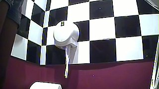 Cute young chick in tight denim shorts urinates in the toilet