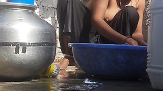 Indian stepsister is preparing to take a bath while washing clothes in the open courtyard of the house