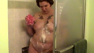 Tattooed fat chick strips to wash her tits and cunt in the shower